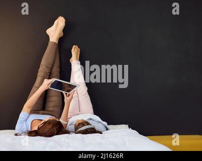 Entertainment in her hands. Full length shot of a mother and her daughter using a digital tablet. Stock Photo