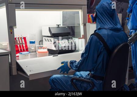 Laboratory assistant during work. Concept - man works in a modern laboratory. Chemist works in chemical protection suit. creation and study of dangero Stock Photo