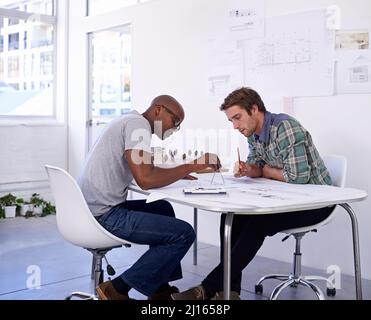 Accuracy is key. Shot of two male architects working together on building plans in the office. Stock Photo