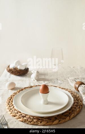 Easter festive dinner with organic egg and decorative nest on linen tablecloth. Vertical format. Close up. Stock Photo