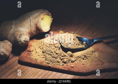 Ginger powder and ginger root on wooden kitchen table Stock Photo