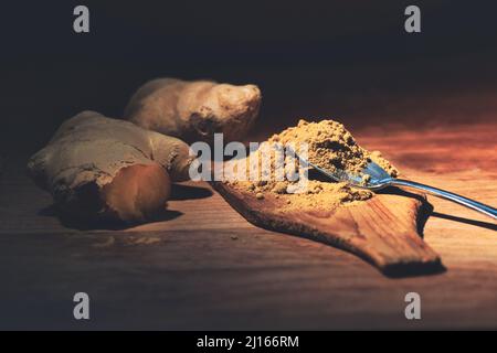 Ginger root and ginger powder on wooden kitchen tablet Stock Photo