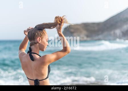 young woman making a ponytail on the beach Stock Photo
