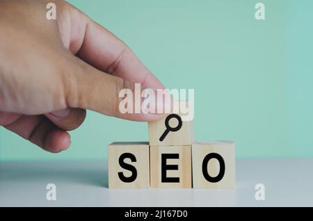 wooden cubes for SEO Search engine optimization magnifying glass icon on background.Copy space. Stock Photo
