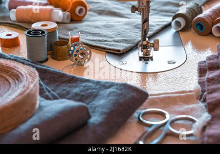 Sewing machine, thread, scissors and fabric close-up. The tailor's workplace. Side view, horizontal. Stock Photo