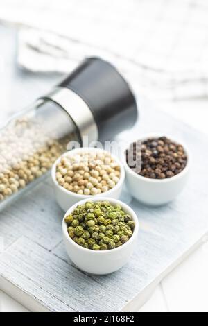 Three different types of pepper spice. Green, white and black peppercorn in the bowls. Stock Photo