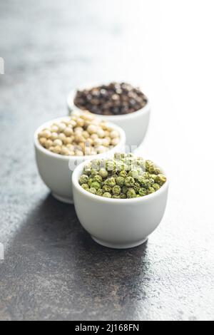 Three different types of pepper spice. Green, white and black peppercorn in the bowls. Stock Photo