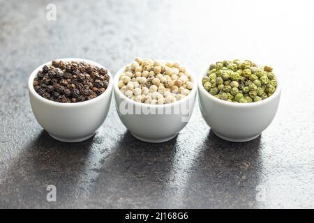 Three different types of pepper spice. Green, white and black peppercorn in the bowls. Stock Photo