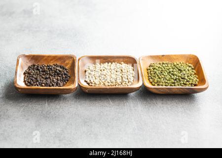 Three different types of pepper spice. Green, white and black peppercorn in the bowls. Stock Photo