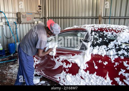 Cape Town, South Africa. 19th Mar, 2022. A worker washes a car at a car wash station in Cape Town, South Africa, on March 19, 2022. TO GO WITH 'Feature: Awareness of water conservation runs deep in Cape Town' Credit: Lyu Tianran/Xinhua/Alamy Live News Stock Photo