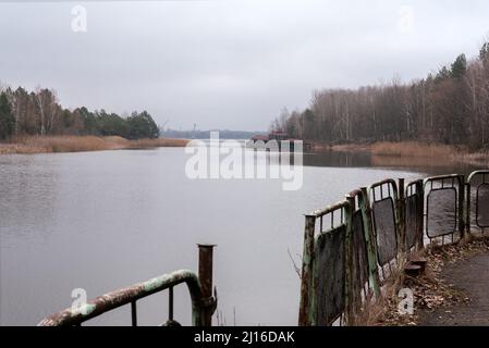 Rusty metal fence and Pripyat river in Chernobyl, Ukraine. Pripyat river and gulf near Pripyat town and Chernobyl Power Plant Stock Photo