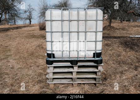 Plastic water tank. Water tank in the form of a container. Water tank on the street. Plastic barrel with a metal frame Stock Photo