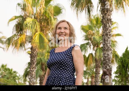 Portrait of a mature woman 50-60 years old against the backdrop of palm trees Stock Photo