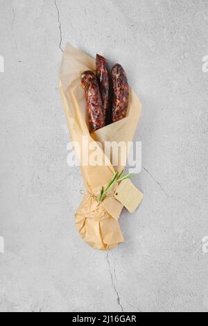 Overhead view of dried sausage made of venison spicy meat and lard in wrapping paper Stock Photo