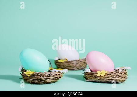 Easter background. Easter eggs in baskets of nests on a blue-green background, in pastel colors. Stock Photo