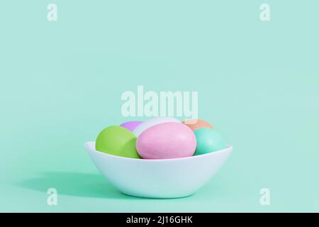 Easter background. A collection of Easter eggs in pastel colors in a plate basket on a blue-green background, with harsh shadows and light. Stock Photo
