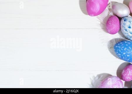Collection of Easter eggs. Chicken eggs painted blue and pink lie on a white wooden background. Creative greeting card with Easter. Frame. Top view. C Stock Photo
