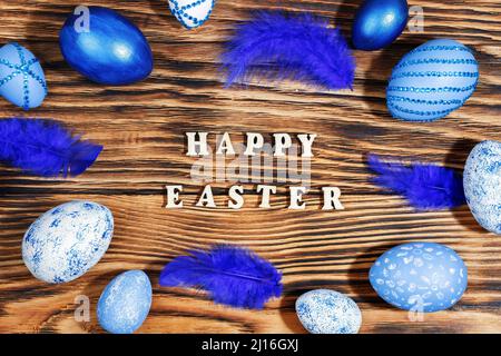 Happy easter, lettering on stylish wooden table, background. Blue and white eggs are everywhere. Colorful Easter eggs, top view. Copyspace. Stock Photo