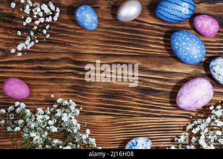 Collection of Easter eggs. Chicken eggs, painted blue and pink, lie on a stylish wooden background with flowers. Creative greeting card with Easter. F Stock Photo