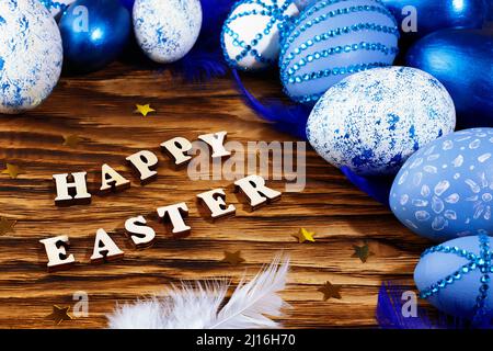 Happy easter, lettering on stylish wooden table, background. Blue and white eggs are everywhere. Colorful Easter eggs, top view. Copyspace. Stock Photo