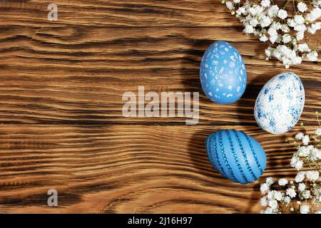 Blue and white, with rhinestones, Easter eggs scattered on a trendy yellow wooden background with flowers . The minimal concept of Easter. Top view. E Stock Photo