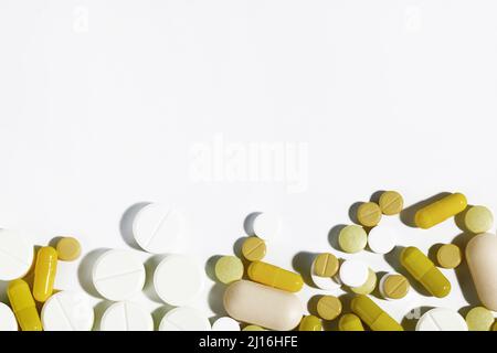 Pills and capsules of different shapes and sizes are isolated on a white background with hard shadows. Medicine and medications concept. Top view. Cop Stock Photo