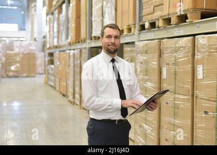 portrait friendly businessman/ manager in suit working in the warehouse of a company - control of inventories Stock Photo