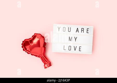 You are my love - quote. Red heart foil balloon and lightbox on a pink background. Stock Photo