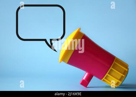 Megaphone, loudhailer on blue background with blank speech bubble. Copy space for text. Stock Photo