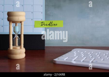 Keyboard, sandglass and calendar with note DEADLINE. Deadline in work, assignment and project Stock Photo
