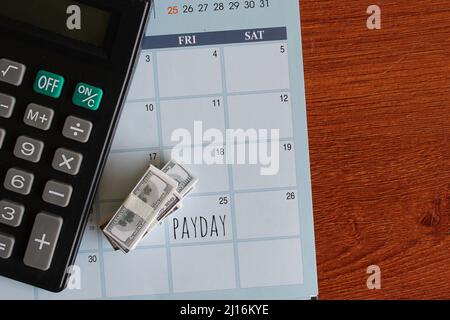 Top view image of banknotes, calculator and PAYDAY written on a calendar. Copy space for text. Stock Photo