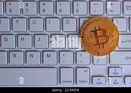 Top view image of glowing bitcoin on top of white keyboard. Cryptocurrency and technology concept. Stock Photo