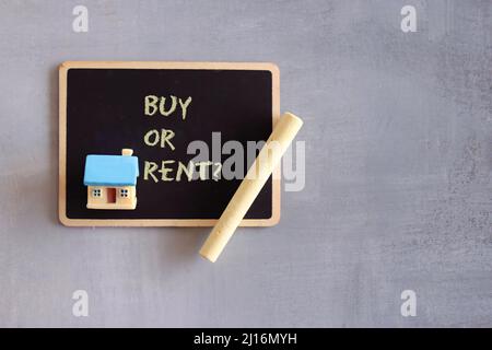 Top view of chalkboard with text BUY OR RENT, toy house and chalk. Copy space. Real estate concept Stock Photo