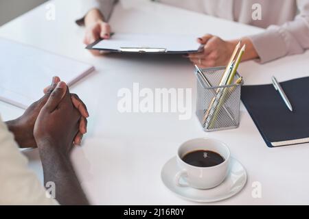 High angle shot of unrecognizable African American man sitting at table in front of his colleague discussing something Stock Photo