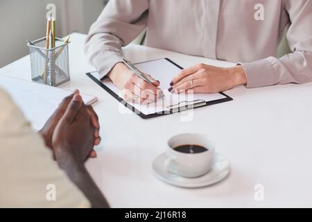 High angle shot of unrecognizable African American man sitting at table in front of his colleague discussing something Stock Photo