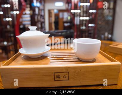 Gong Fu Cha brewing. Beautiful white porcelain (Gaibei/ Gaiwan & tea cup) set on a bamboo tray. Perfect for tea tasting. Lock Cha Tea House, Hong Kong Stock Photo