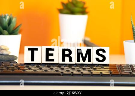gray word term from small wooden letters on a blue table Stock Photo