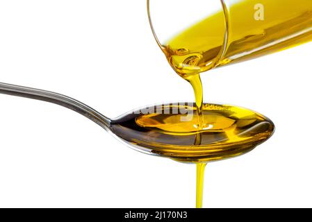 Extra virgin oil poured from bottle into spoon, isolated on white background, clipping path Stock Photo