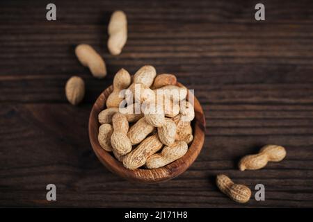 Pile of Peanuts in a bowl on a dark wooden background. Fresh nuts in their shells. Stock Photo