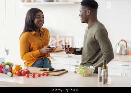 Happy Black Man And Woman Drinking Wine While Preparing Food In Kitchen Stock Photo