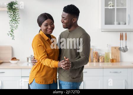 Young Happy Black Spouses Dancing Together In Kitchen, Having Fun At Home Stock Photo