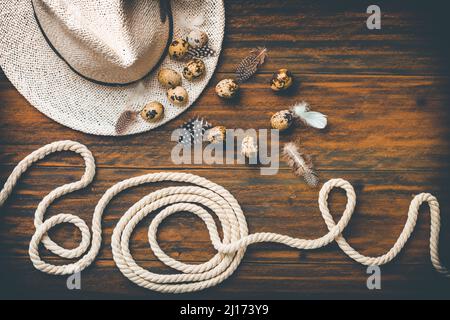 Spring and country life, Easter still life with quail eggs, hat and rope on wooden background Stock Photo