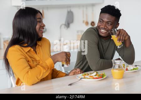 Cheerful young black couple sitting at table and eating tasty breakfast together Stock Photo