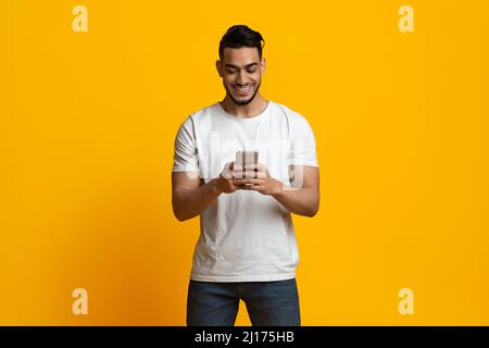 Happy middle eastern man using smartphone and smiling Stock Photo