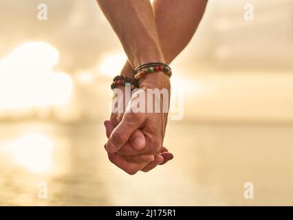 Holding your hand while we wonder the beach. Closeup shot of an unrecognizable couple holding hands while spending the day by the beach. Stock Photo