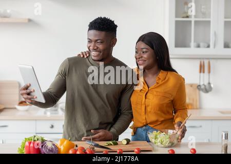 Portrait Of Young Black Couple With Digital Tablet Posing In Kitchen Interior Stock Photo