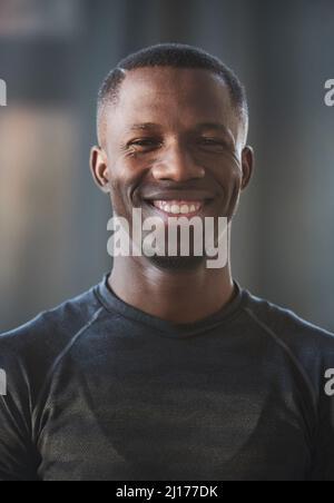 Vertical medium close-up portrait of joyful young African American man wearing dark gray T-shirt standing indoors smiling at camera Stock Photo