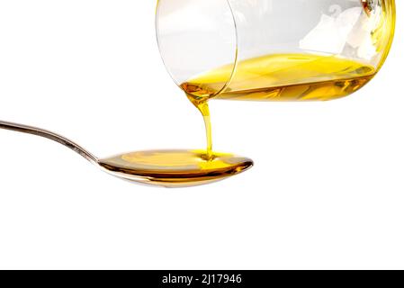 Extra virgin oil poured from glass into spoon, isolated on white background, clipping path Stock Photo