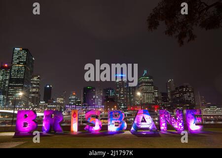 Brisbane Australia - April 27 2016; City skyline lights at night beyond bright illuminated city name sign along river walk. Stock Photo