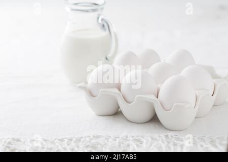 Organic milk and fresh eggs on white kitchen table Stock Photo